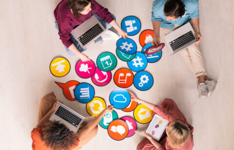 Above view of young social media marketers sitting on floor and using computers while analyzing marketing tools